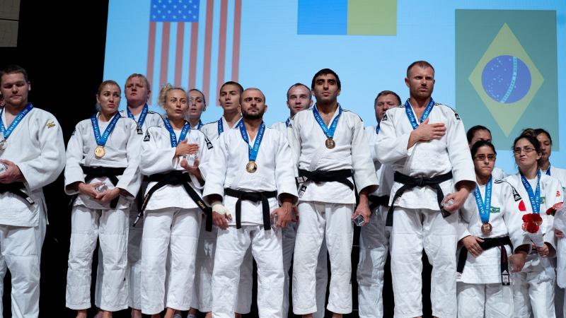 A group of vision impaired female and male judokas on the podium