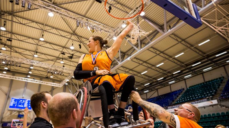 Dutch female being lifted up on her wheelchair to the basketball hoop