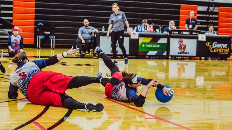 A female goalballer slides to block the ball from entering the goal