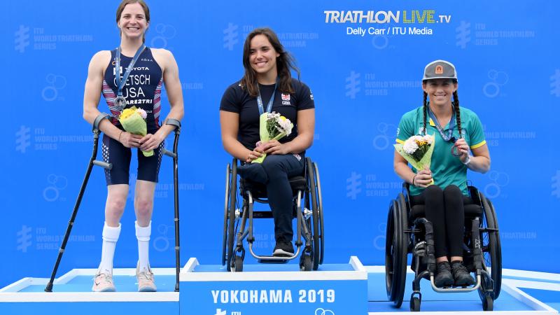 Three female triathletes on a podium smiling