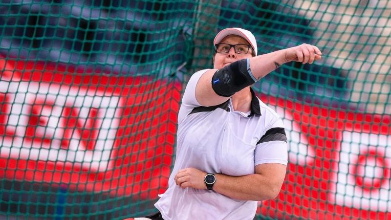 Polosh woman sits in chair and throws a discus