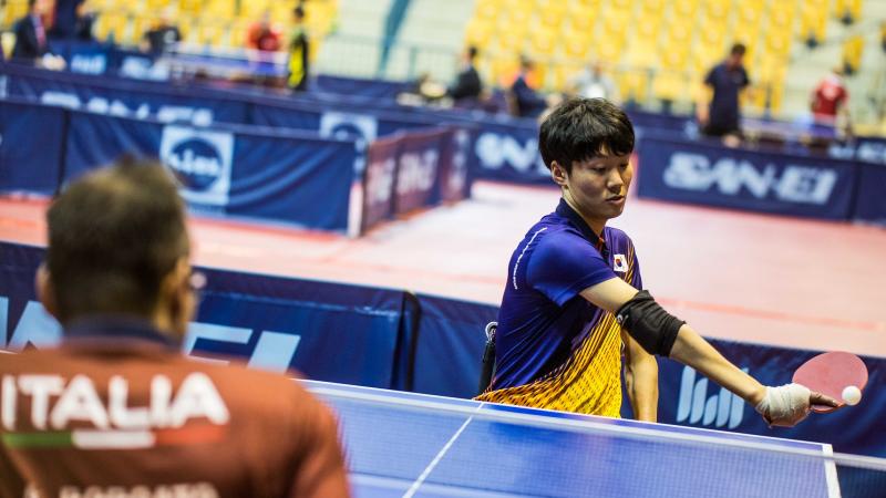 Male Korean table tennis playe in wheelchair hits a backhand shot
