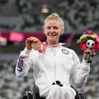 Woman smiles with medal and gift