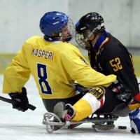 A picture of 2 men in sledges playing ice hockey