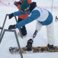 A picture of a man with a prosthesis practising snowboard