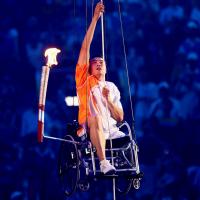 Hou Bin climbing up a rope in a wheelchair.