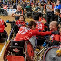 a group of Japanese wheelchair rugby players celebrate on the court