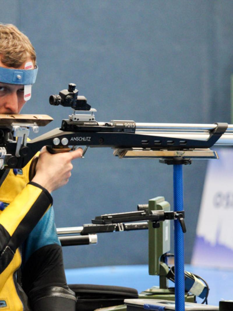 A man with a rifle in a sitting position at a shooting range