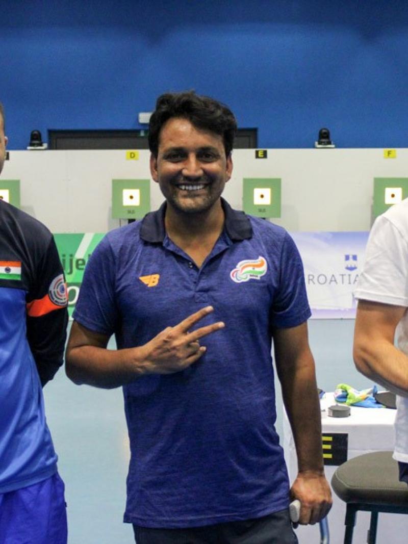 Three male pistol shooters pose for a photo