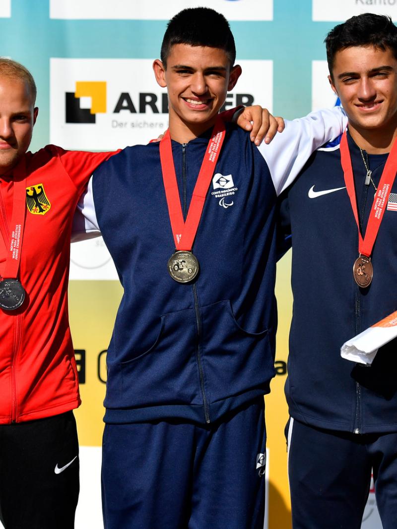 Three young men on a podium with their medals