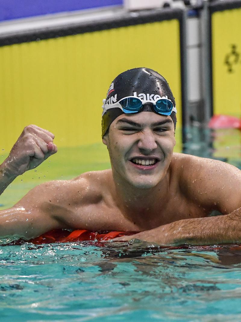 a male swimmer in the water giving a victory fist pump