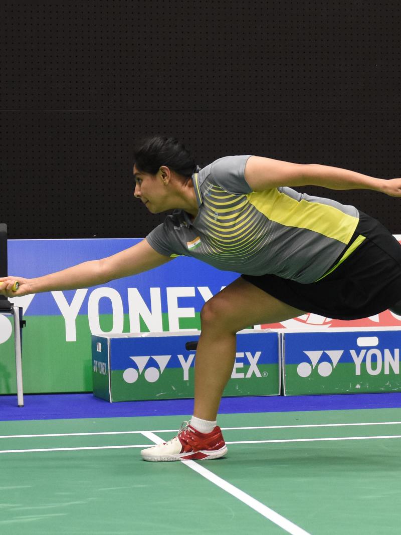a female Para badminton player with a prosthetic leg reaches for a shot