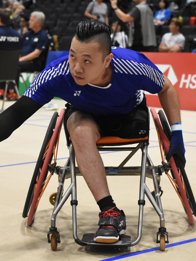 Hong Kong badminton player in wheelchair leans over to return a shot