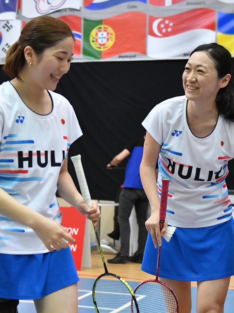 two female standing Para badminton players laughing together on court
