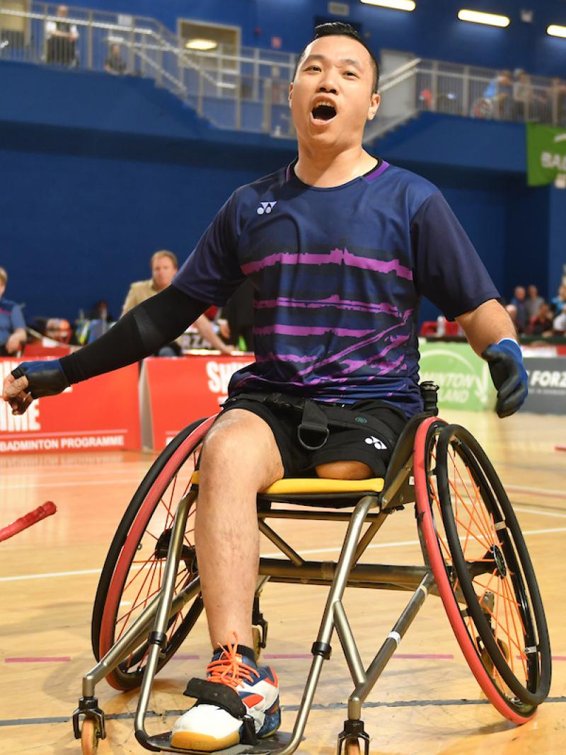a male Para badminton player in a wheelchair cheers after scoring a point