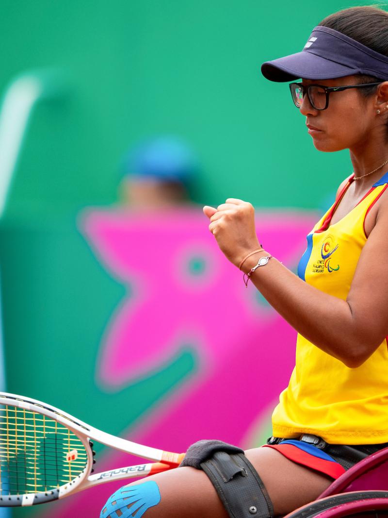 a female wheelchair tennis player clenches her fist on the court
