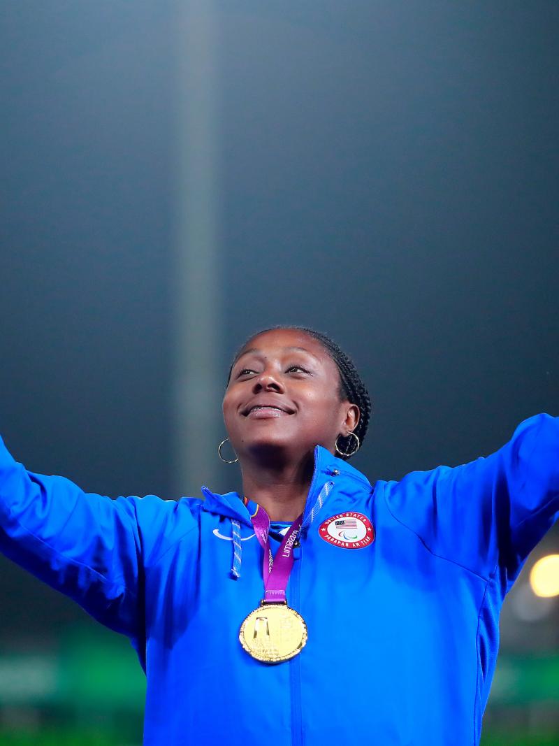a female Para athlete giving a victory hand gesture on the podium