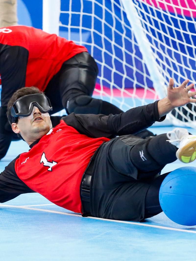 a male goalball player saves a shot with his legs