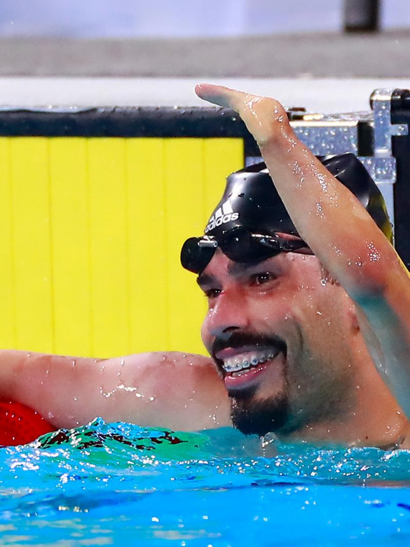 a male Para swimmer raises his arm in celebration in the pool