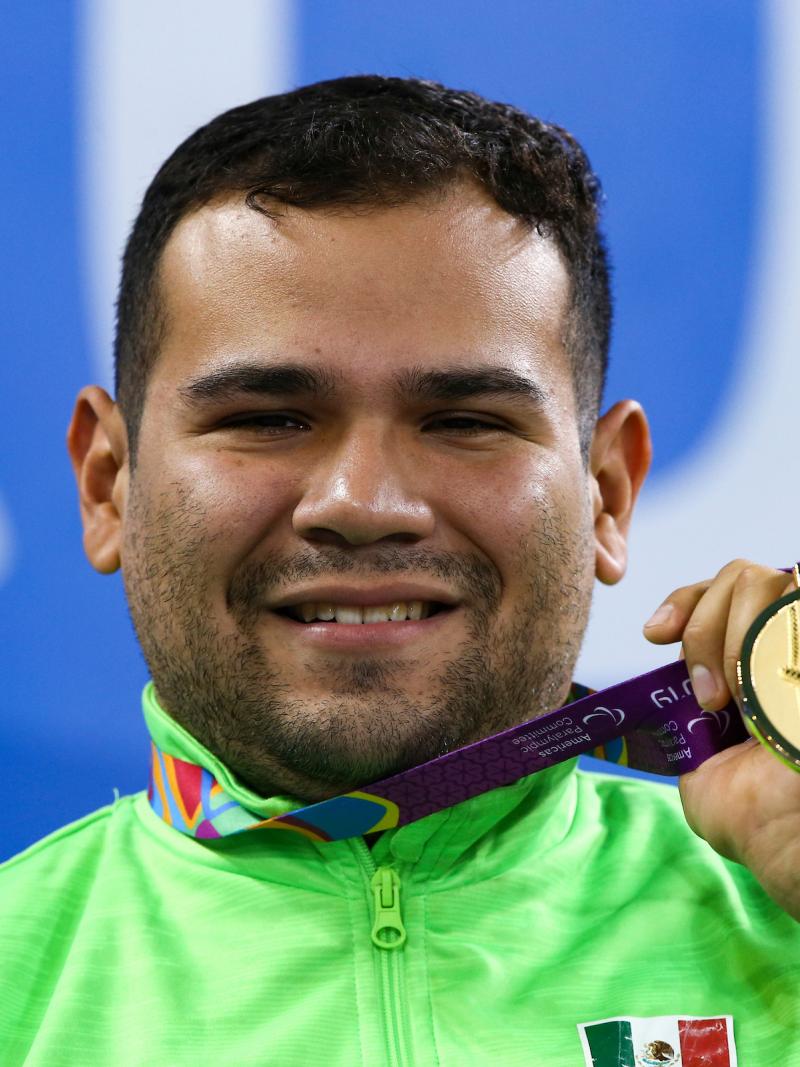 a male Para swimmer holds up his gold medal