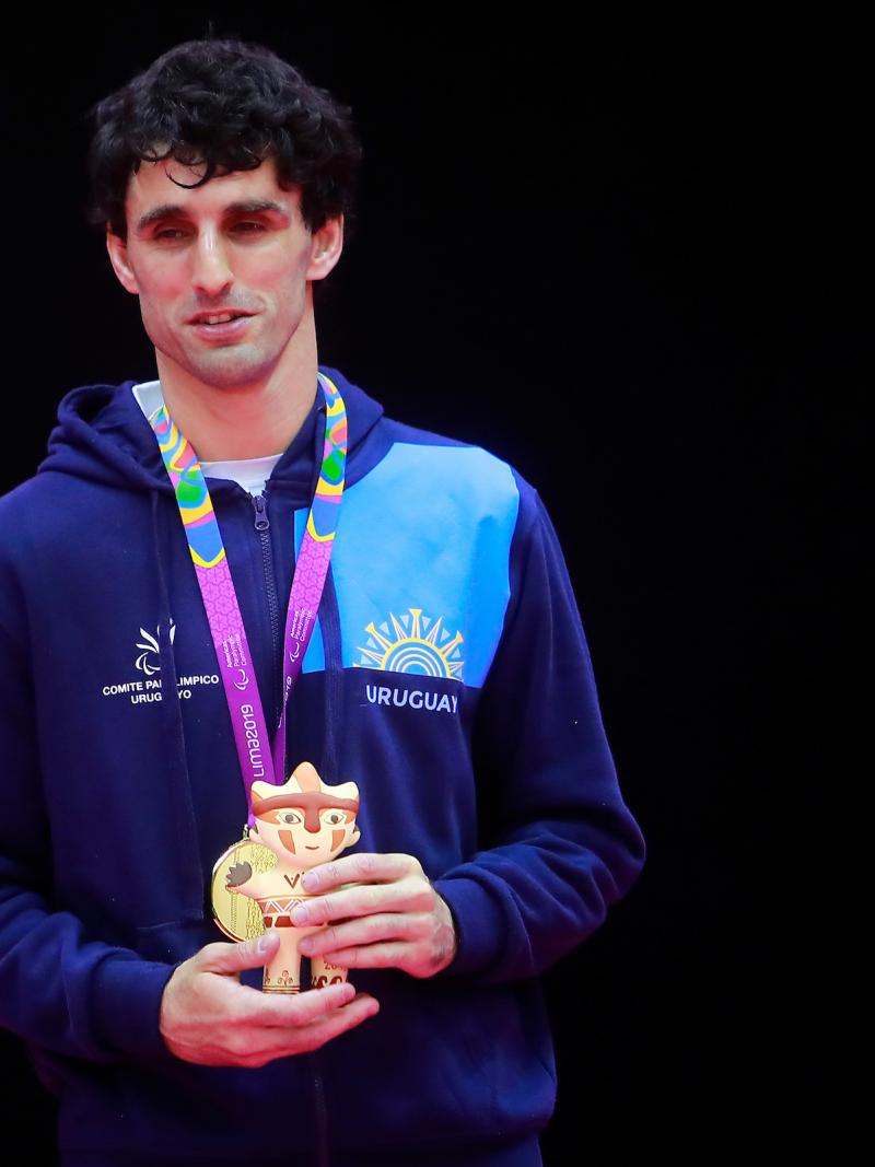 a male judoka stands on the podium with his gold medal