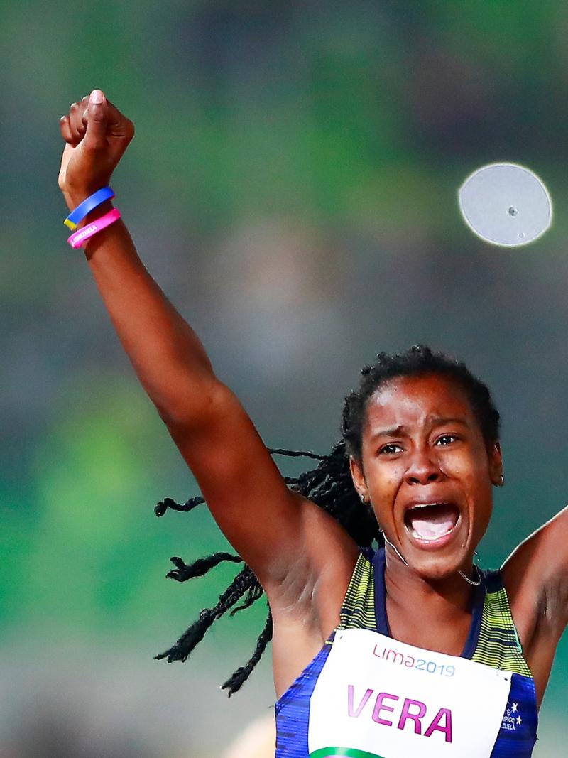 a female Para athlete raises her arms in celebration on the finish line