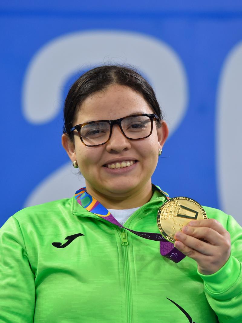 a female Para swimmer holding up her gold medal