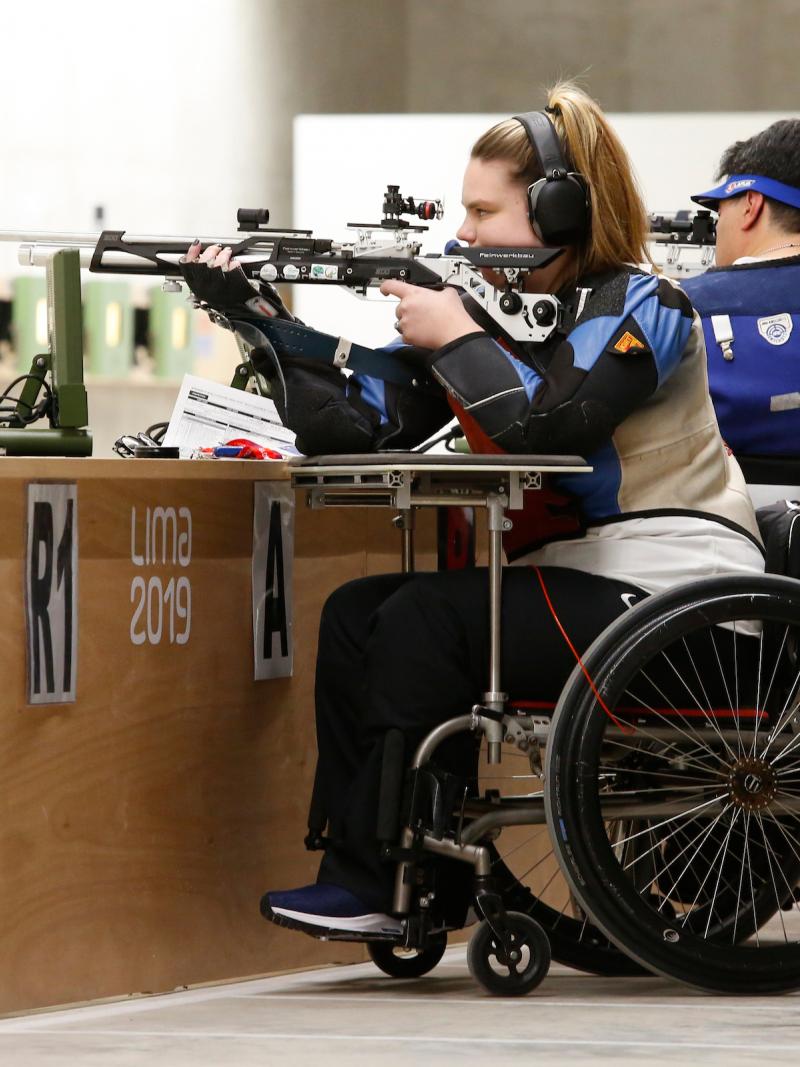 a female Para shooter in a wheelchair fires a rifle at the target