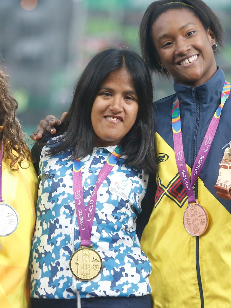 three female Para athletes with their medals on the podium