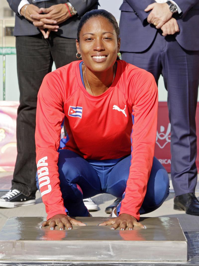 a female Para athlete places her hands in cement to leave prints
