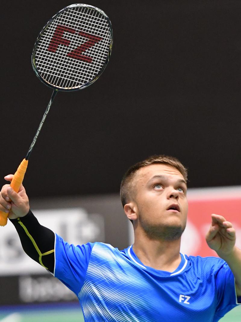 English short statured badminton player looks up about to hit the birdie