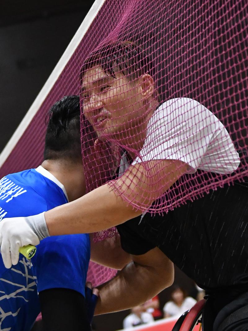 Two male wheelchair badminton players hug each other