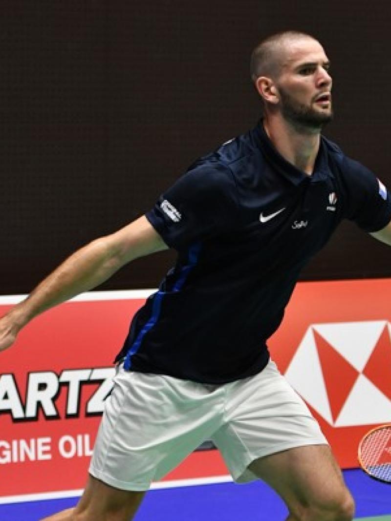French male badminton player about to lunge for the birdie