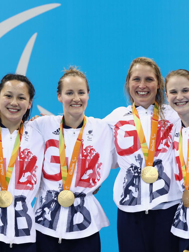 four female Para swimmers on the podium holding their gold medals 