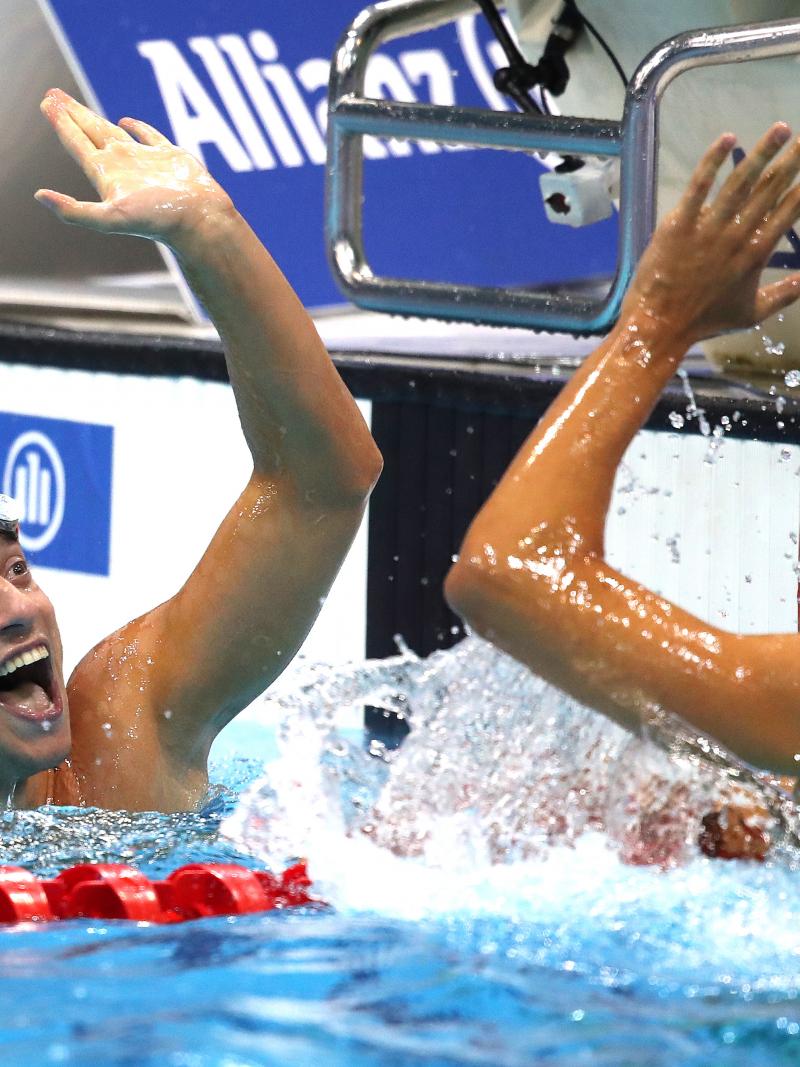 two male Para swimmers high fiving in the water