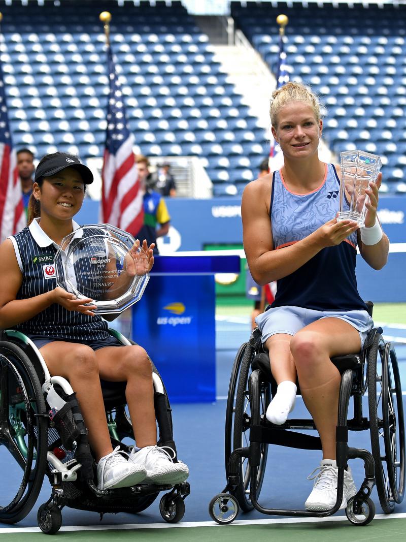 two female wheelchair tennis players holding up trophies