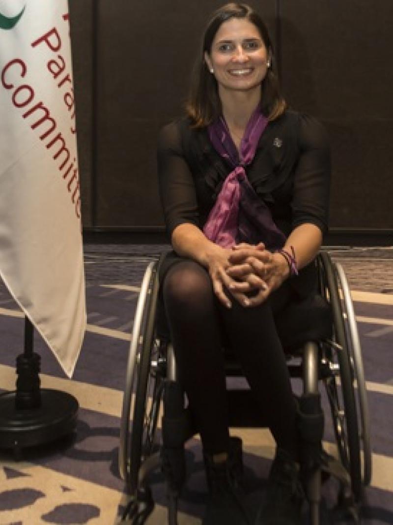 a female wheelchair athlete next to a flag