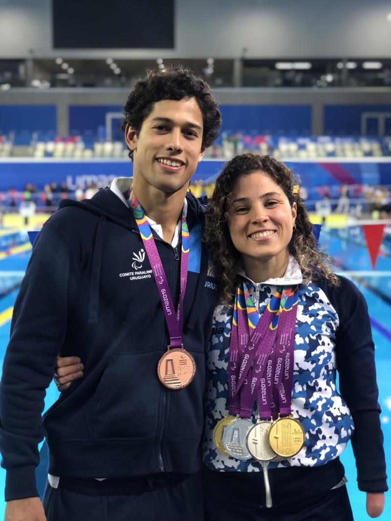 a male and female Para swimmer by the pool with their arms round eachother