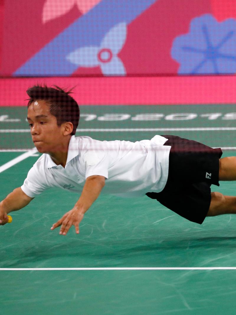 a male Para badminton player dives to hit a shot