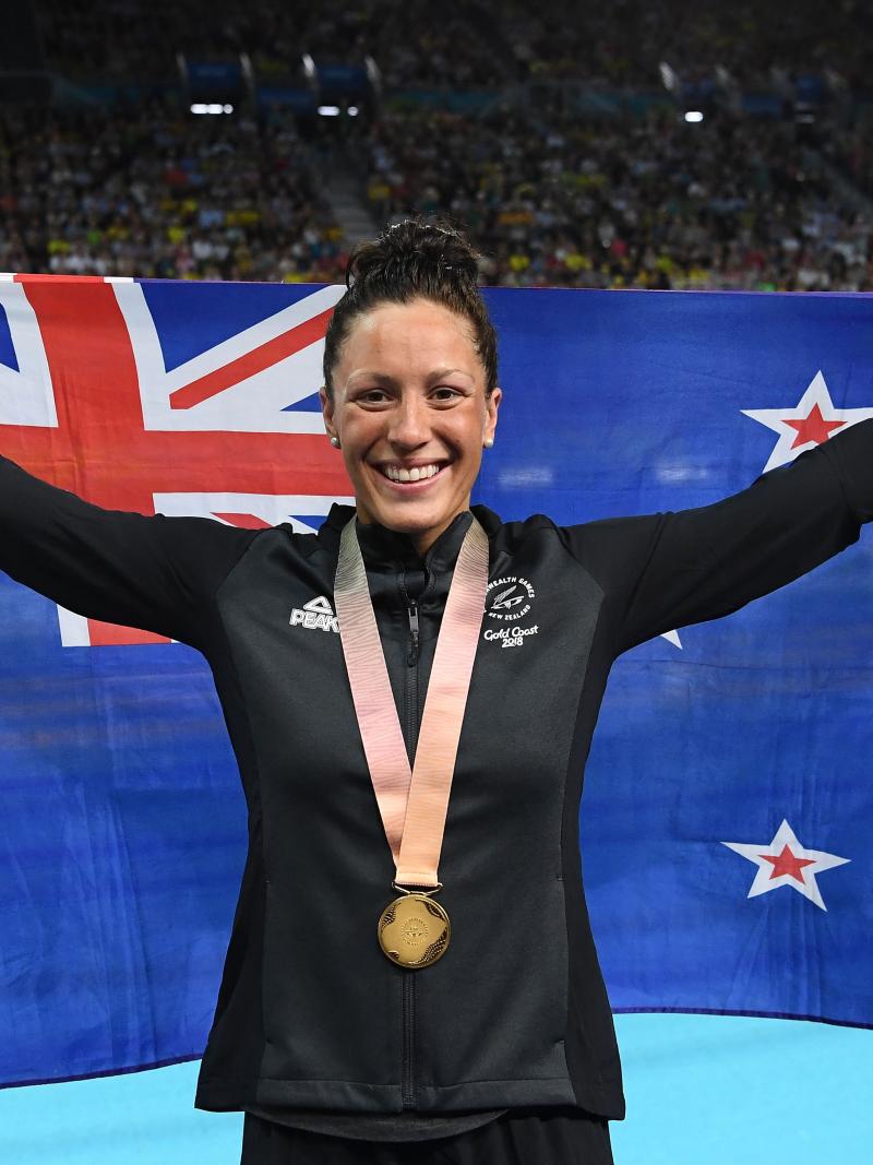 female Para swimmer holding up a New Zealand flag