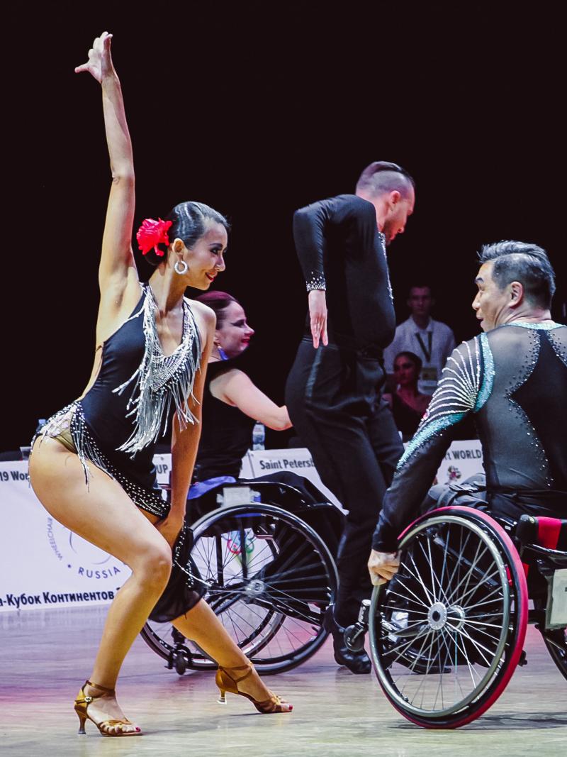 Female standing dancer dances with male wheelchair partner
