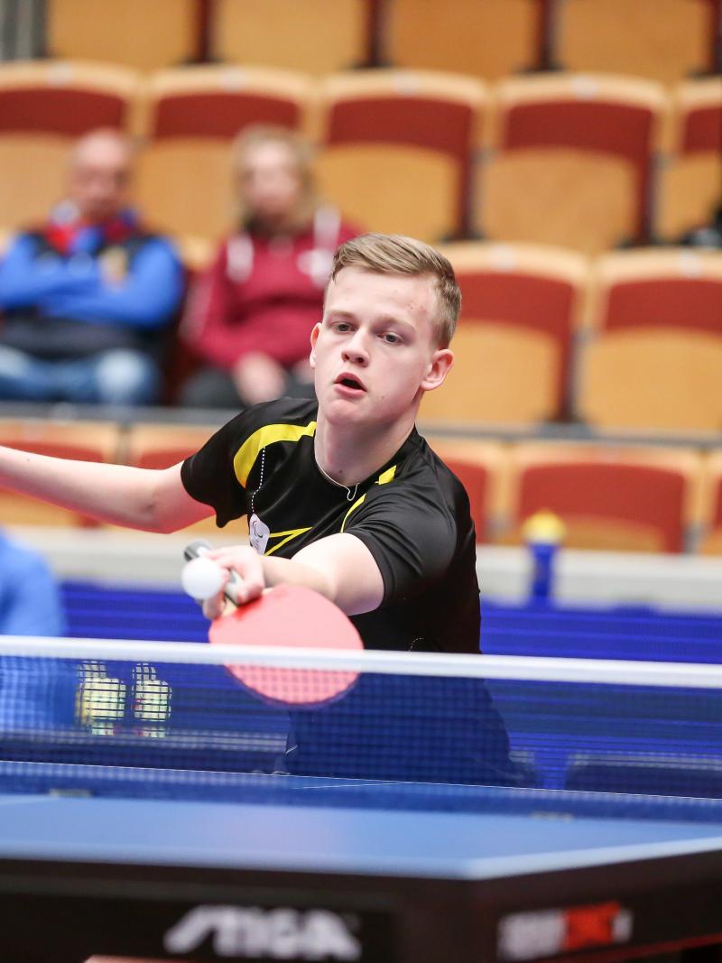 Teenage male table tennis player returns ball