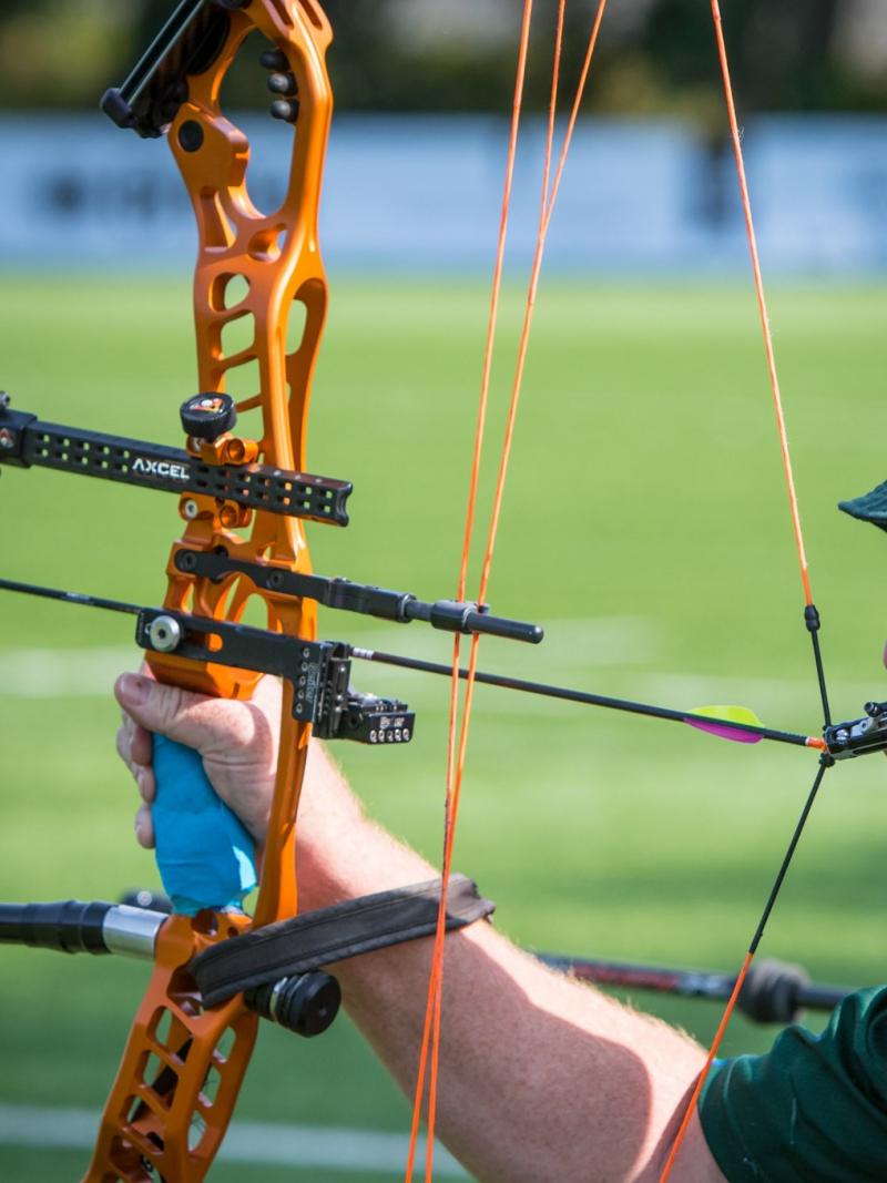Male archer with missing left arm shoots arrow with mouth