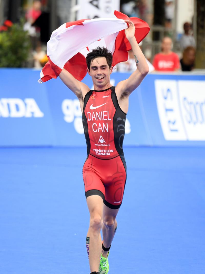 Male triathlete with arm disability holds Canadian flag