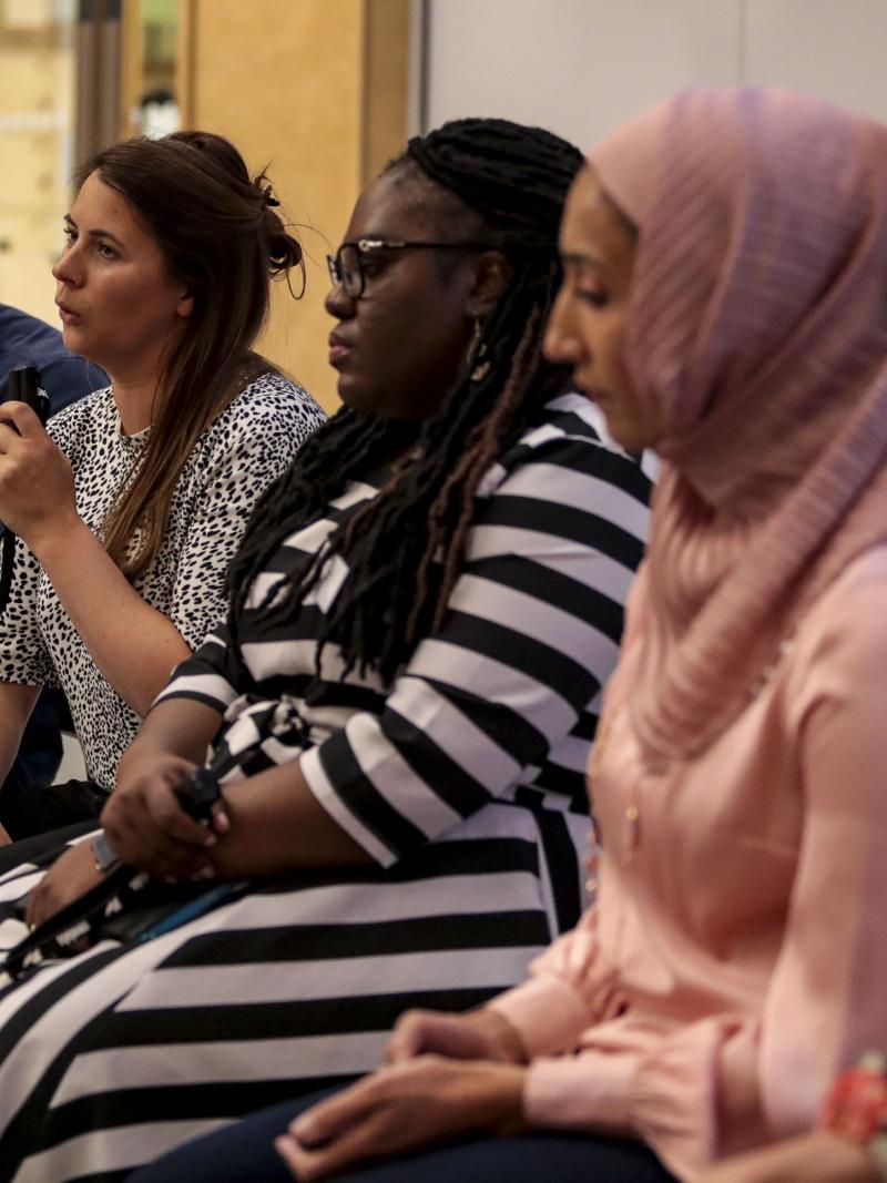 Speakers sitting next to each other with one of them talking with a microphone