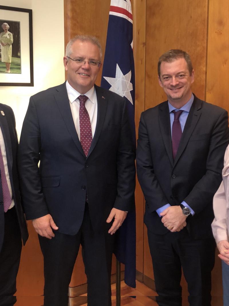 Three men and a woman posing for a picture with a flag of Australia behind them