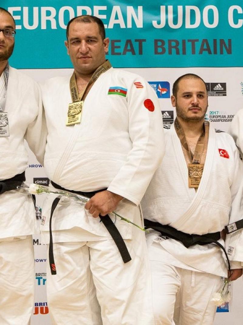 Four male medal winners on a podium