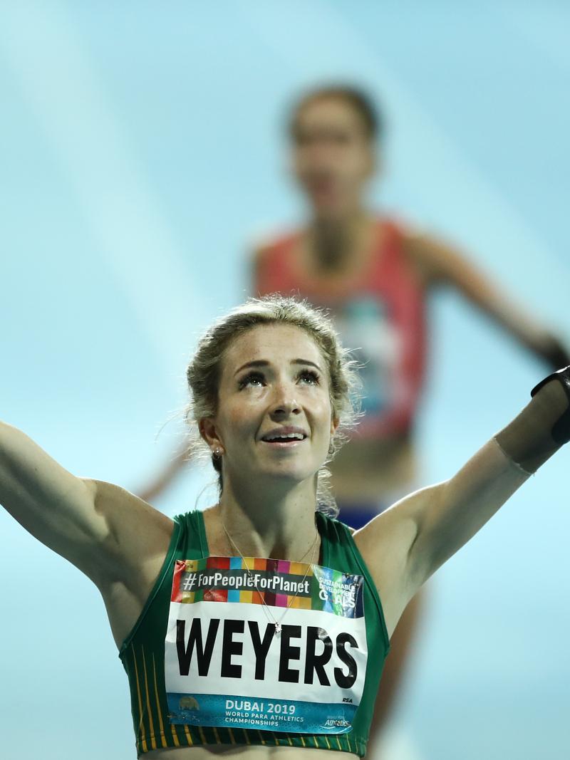 A female runner with a prosthetic arm celebrating
