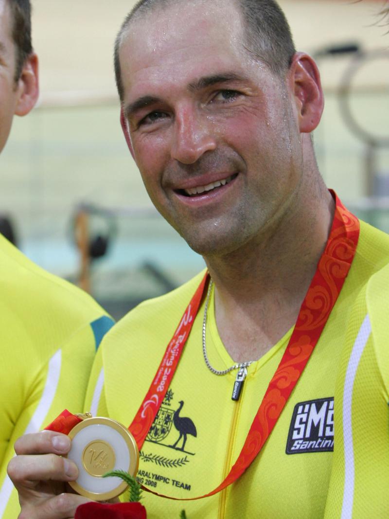 Kieran Modra holds gold medal and smiles to the camera