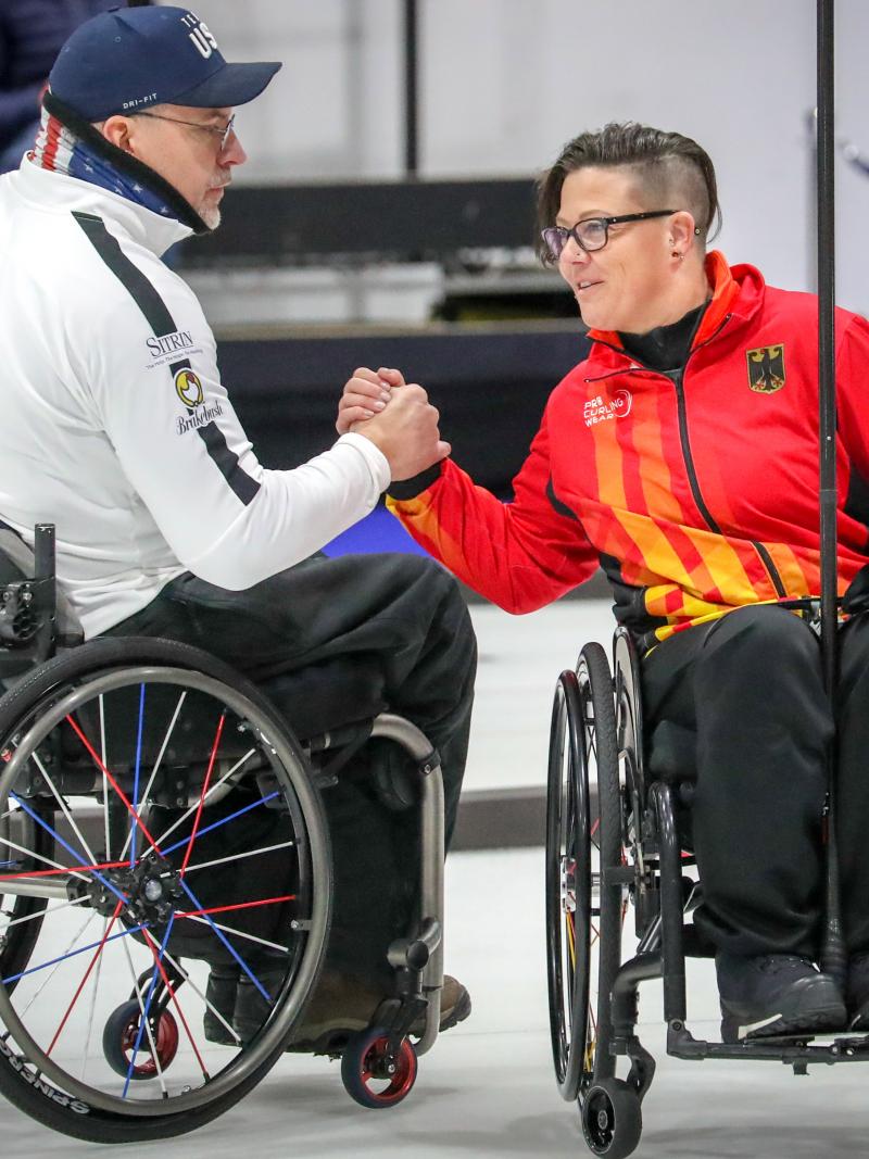 Two wheelchair curlers shake hands
